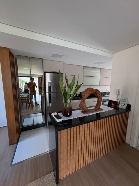 Cozinha integrada com bancada revestida em ripado de madeira