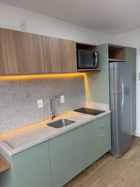 Cozinha planejada em verde sálvia com bancada de granito e iluminação de LED